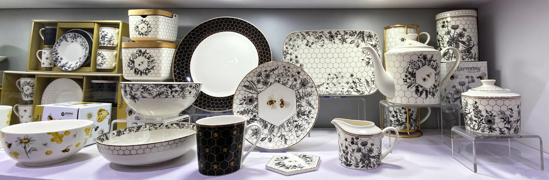 Bee and honeycomb themed ceramic tableware collection displayed on a shelf